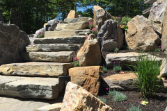 Pocket beds along the staircase are planted with tall grasses and colorful flowers.