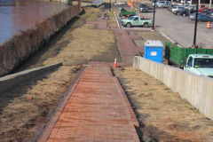 Sidewalk installation in progress. Chain link fence along river to be replaced with wrought iron.