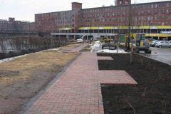 Seating areas awaiting benches with planting beds on right side.